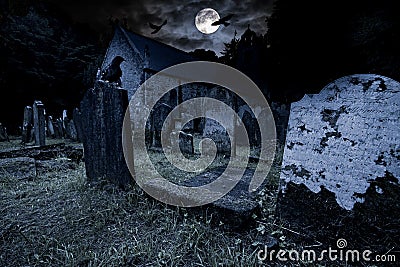 Old graveyard with ancient tombstones grave stone and old church front of full moon black raven dark night spooky horror Stock Photo