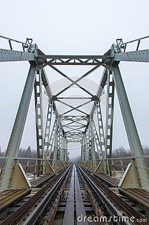 An old railway bridge and rails running into foggy distance Stock Photo