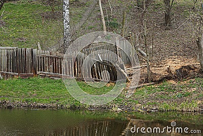 Old gray wooden broken fence in green grass Stock Photo