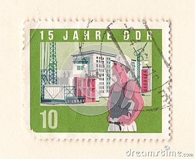 An old green east german stamp with an image of a construction worker on a building site with a crane Editorial Stock Photo