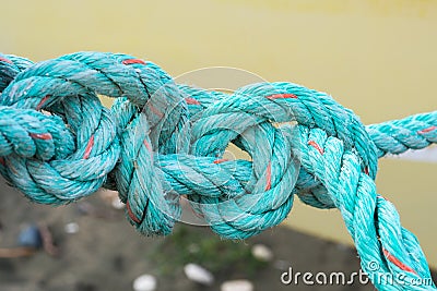 Old green rope knotted on a yellow background. Knot. Insoluble problem concept Stock Photo