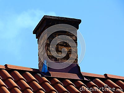 Old decaying chimney on light brown clay tile roof Stock Photo