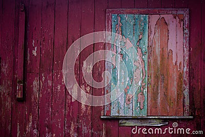 Old grunge and weathered home facade with green window and red wall planks texture background Stock Photo