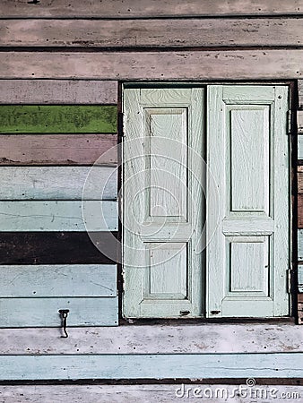 Old grunged wooden window frame painted white vintage with old colourful plywood wall. Antique window frame and old panes. Old Stock Photo