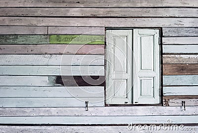 Old grunged wooden window frame painted white vintage with old colourful plywood wall. Antique window frame and old panes. Old Stock Photo