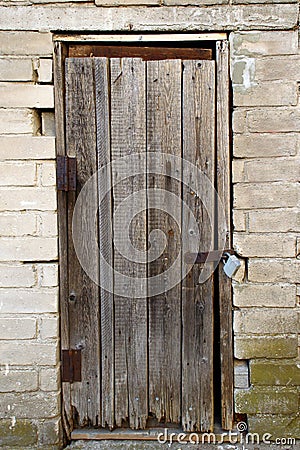 Old Halloween spooky wooden door with a lock in white brick wall Stock Photo