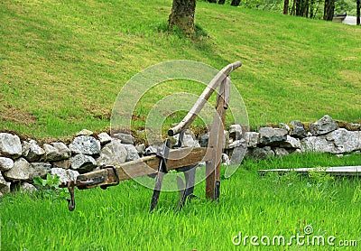 Old hand plough lying in a green field Stock Photo