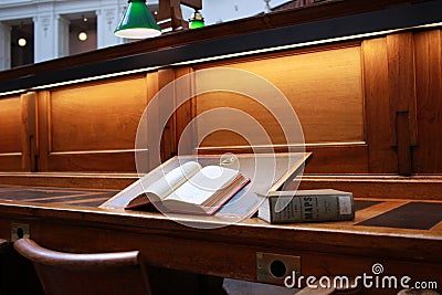 old hard cover book sitting at an old traditional timber reading desk under a glass lamp in an old state library in Melbourne, Editorial Stock Photo