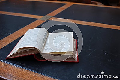 old hard cover book sitting at an old traditional timber reading desk under a glass lamp in an old state library in Melbourne, Editorial Stock Photo