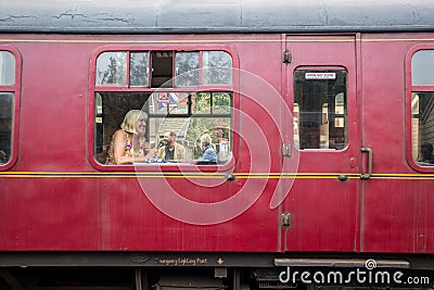 Old heritage train railway cariage with smiling woman seated inside looking out of the window Editorial Stock Photo