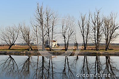 Old house behind the trees reflected in the river Stock Photo