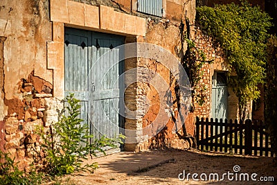 Old house with big light blue gate in one of the most beautiful villages of France Roussillion, Provence. Stone walls painted in Stock Photo