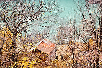 Old house near lake, surrounded by autumn trees, hunting lodge in forest Stock Photo