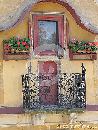 An old house with small window and blooming geraniums. Stock Photo