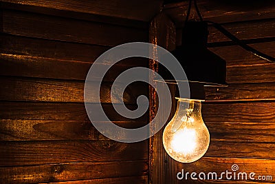An old incandescent lamp illuminates the corner of a dark room. Electrification, payment for electricity Stock Photo
