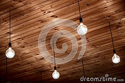 Old incandescent lamps hang on wires on a wooden ceiling. Retro design Stock Photo