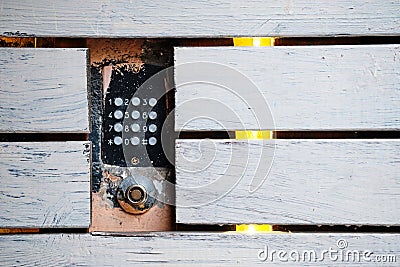 An old intercom with a magnetic key space mounted in the facade. There are wooden white boards around Stock Photo