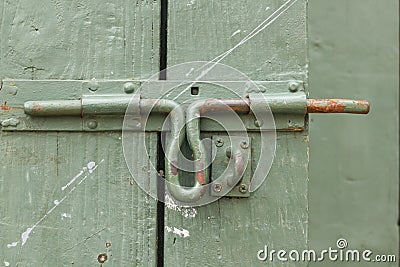 Old iron bolt at the green wood door. Stock Photo