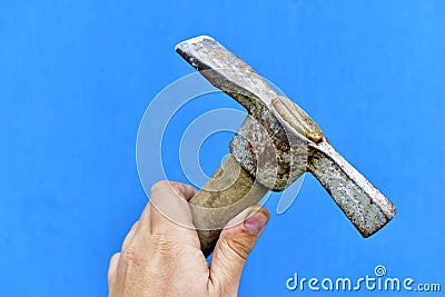 Old iron pickaxe in hand on a blue background Stock Photo