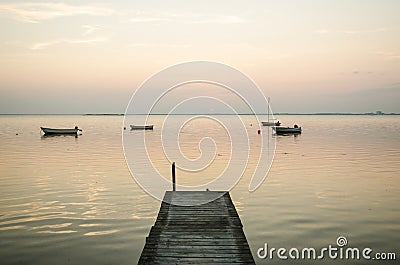 Old jetty with anchored rowing boats in the water Stock Photo