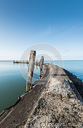 Old jetty with wooden bollards on a windless day Stock Photo