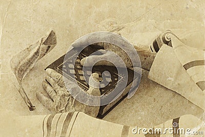 Old Jewish man hands holding a Prayer book, praying, next to tallit and shofar (horn). Jewish traditional symbols. Stock Photo