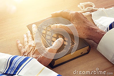 Old Jewish man hands holding a Prayer book, praying, next to tallit. Jewish traditional symbols. Rosh hashanah jewish New Year ho Stock Photo