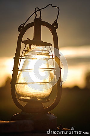 The old kerosene lantern on a tractor at sunset Stock Photo
