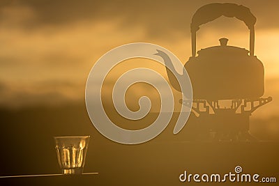 Old kettle silhouette and glass on sunrise Stock Photo