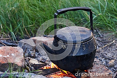 An old kettle stands on a fire in nature Stock Photo
