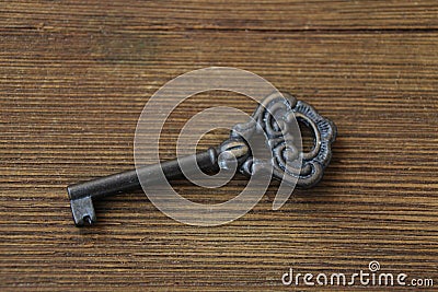 Old key lies on an old wooden table, natural textures, the concept of discovery, secrets, answers, answers to difficult questions Stock Photo