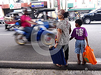 An old lady and a child waits by the roadside for a public transportation vehicle Editorial Stock Photo