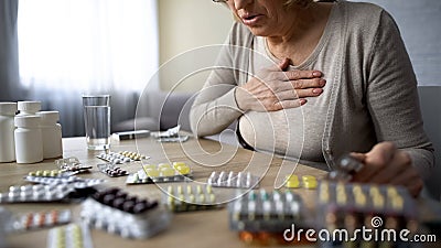 Old lady feeling unwell, looking for pills, sick woman suffering heart problem Stock Photo