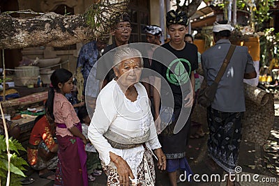 An old lady in front and other people in traditional Balinese clothing on the ceremony of cremation, Bali Island, Indonesia Editorial Stock Photo