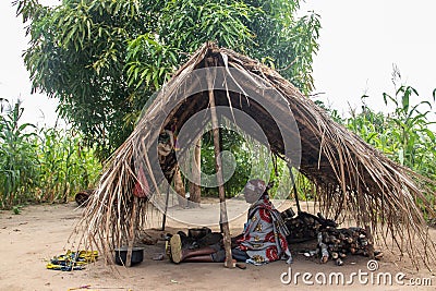 Old lady from Makonde tribe sitting in primitive kitchen and preparing local traditional meal Editorial Stock Photo