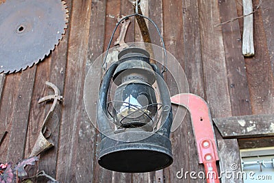 Old Lantern and Farm Tools On Cabin Wall Stock Photo