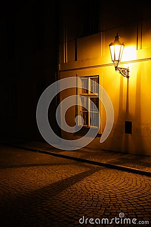 Old lantern illuminating a dark alleyway medieval street at night in Prague, Czech Republic. Low key photo Stock Photo