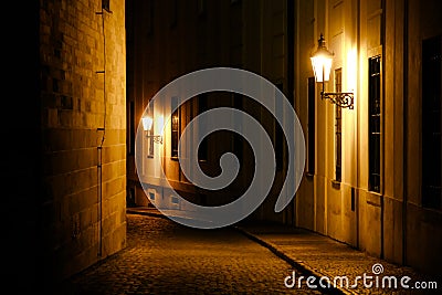 Old lanterns illuminating a dark alleyway medieval street at night in Prague, Czech Republic. Stock Photo