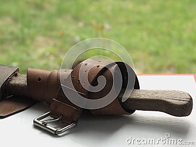 Old leather belt a serpentine on the ax. Ax and belt - after work . Stock Photo