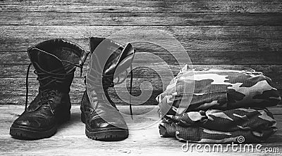 Old leather black mens boots ankle boots and a military uniform on wooden background front view closeup Stock Photo