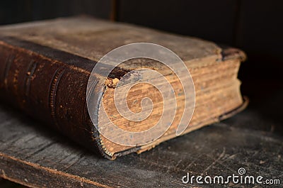 Old leather bound book laying on a dusty wooden bookshelf Stock Photo