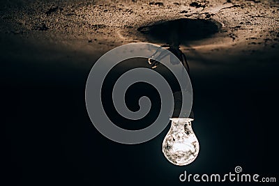 Old light bulb glowing in the dark basement. electricity improvisation at construction site. Stock Photo