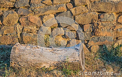 An old log next to an old stone wall Stock Photo