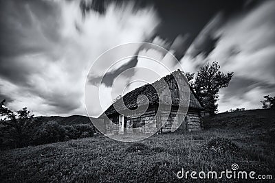 An old, long-abandoned house, against the background of a cloudy sky, shot on a long exposure. Abandoned house in West Ukraine.Old Stock Photo