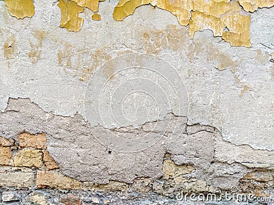 Old looking facade wall with pieces of old yellow facade left of a color that used to be with rough texture of bricks showing and Stock Photo