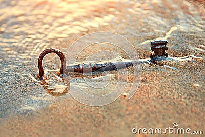 An old lost key in the sand is a newfound opportunity. The concept of success, luck and unexpected wealth Stock Photo