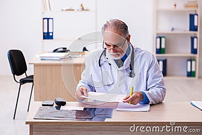 Old male doctor cardiologist looking electrocardiogram Stock Photo