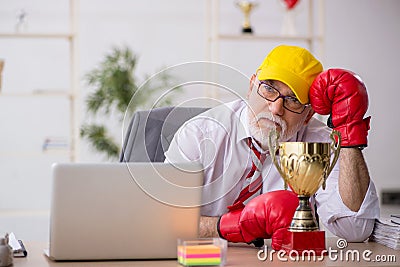 Old male employee boxer being awarded with golden cup Stock Photo