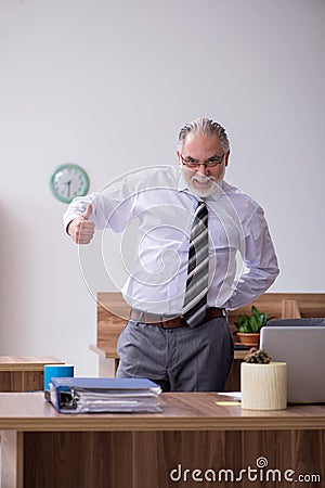 Old male employee suffering from radiculitis at workplace Stock Photo