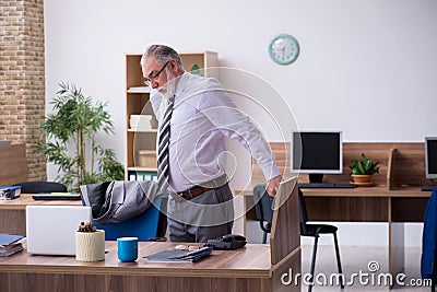 Old male employee suffering from radiculitis at workplace Stock Photo